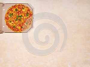 Juicy tasty pizza in a cardboard box on a light beige background with a place for a signature