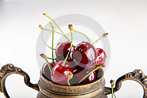 Juicy wet cherries in brass vessel