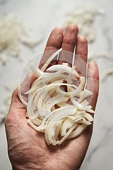 Julienne cuted onions on mans hand. Photo show how does julienne sliced or pole to pole to root to stem or half rings