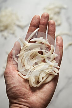 Julienne cuted onions on mans hand. Photo show how does julienne sliced or pole to pole to root to stem or half rings