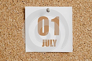 july 01. 01th day of the month, calendar date.White calendar sheet attached to brown cork board.Summer month, day of the