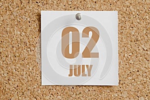 july 02. 02th day of the month, calendar date.White calendar sheet attached to brown cork board.Summer month, day of the