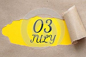 july 03. 03th day of the month, calendar date.Hole in paper with edges torn off. Yellow background is visible through