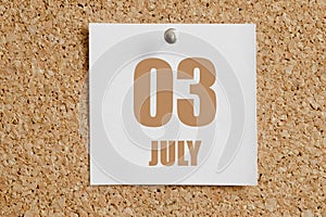 july 03. 03th day of the month, calendar date.White calendar sheet attached to brown cork board.Summer month, day of the