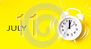 July 11st . Day 11 of month, Calendar date. White alarm clock with calendar day on yellow background. Minimalistic concept of time