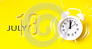 July 18th. Day 18 of month, Calendar date. White alarm clock with calendar day on yellow background. Minimalistic concept of time