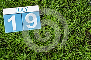 July 19th. Image of july 19 wooden color calendar on greengrass lawn background. Summer day, empty space for text