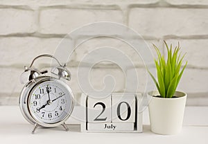 July 20 Wooden calendar with date and table clock with bells on the table or shelf. It`s July.High summer