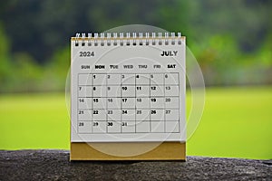 July 2024 white calendar with green blurred background.