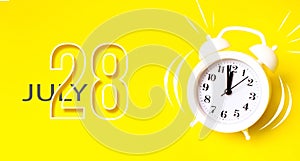 July 28th. Day 28 of month, Calendar date. White alarm clock with calendar day on yellow background. Minimalistic concept of time