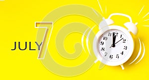 July 7th. Day 7 of month, Calendar date. White alarm clock with calendar day on yellow background. Minimalistic concept of time,