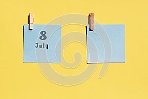 July 8st. Day of 8 month, calendar date. Two blue sheets for writing on a yellow background. Top view, copy space. Summer month,