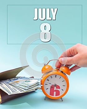 July 8th. Hand holding an orange alarm clock, a wallet with cash and a calendar date. Day 8 of month.