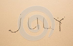 July - written in sand on beach texture, months year series