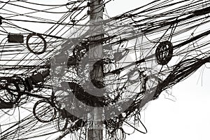 A jumble of electrical and telephone wires attached to a pole in Bangkok, Thailand