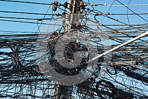 A jumble of electrical and telephone wires attached to a utility pole in Thailand