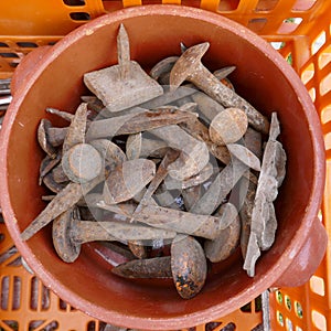 Jumble of old rusty nails and hand tools in a orange plastic box.