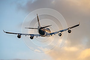 Jumbo jet four big engines flying off taking tourists abroad from airport on holiday into golden sunset summer sky.