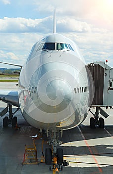 Jumbo Plane Head. Big passenger plane at gate at the airport front view. Sunny cloudy day.