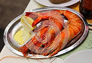 Jumbo shrimps with lemon and sauce on metal plate