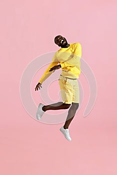 Jump. Happy black man jumping in air laughing on pink background