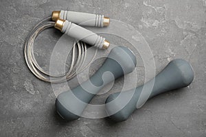 Jump rope and dumbbells on grey background