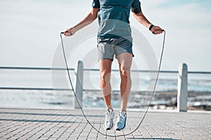 Jump rope, fitness and man by a sea promenade with training, sports and exercise equipment. Health, jumping and body
