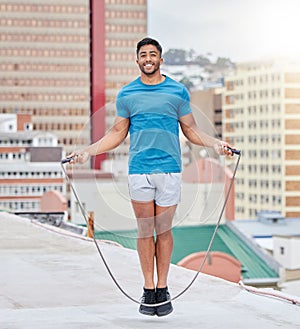 Jump rope, fitness and portrait of a man on a rooftop, sports training and cardio in the urban city. Energy, jumping and