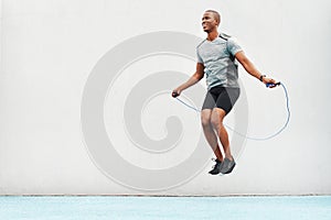 Jump, rope and space with black man skipping in stadium for sports, workout and cardio. Performance, health and body