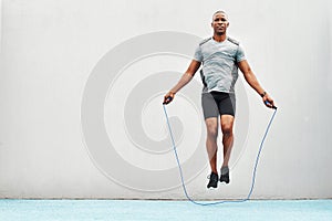 Jump, rope and training with black man skipping in stadium for sports, workout practice and cardio. Health and body with