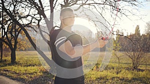 Jump rope workout of a handsome Caucasian boy in the autumn park on sunset. Young man in sportwear training outdoors