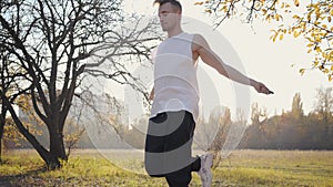 Jump rope workout of a young Caucasian boy in the autumn park on sunset. Man in sportwear training outdoors. Healthy