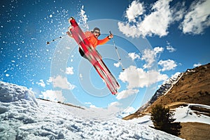 Jump with a trick in the ozdou athlete skier with a kicker on a sunny day of spring or winter against the blue sky and