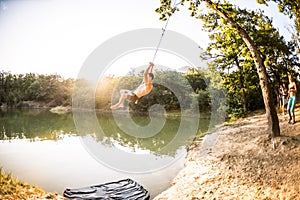 Jump into the water. A man is resting on the nature. A swing from a rope and a stick. Active recreation in nature. Friends have