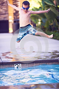 Jumping boy in the air, heading into the pool