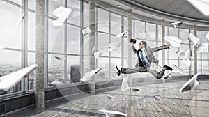 Jumping businessman in office . Mixed media