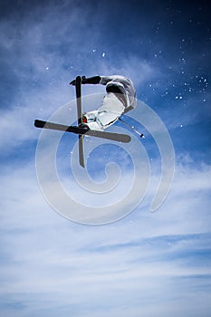 Jumping freestyle skier on blue sky background.
