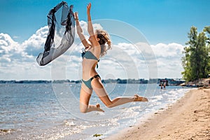 Jumping happy girl on the beach, fit sporty healthy body in bikini