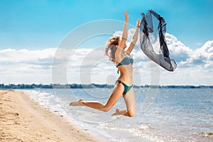 Jumping happy girl on the beach, fit sporty healthy body in bikini