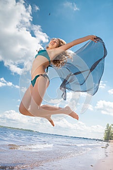 Jumping happy girl on the beach, fit sporty healthy body in bikini