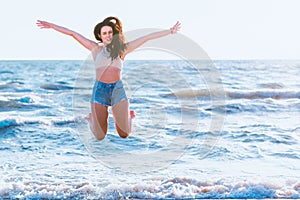 Jumping happy girl on a beach, fit sporty sexy body, woman enjoys sunset freedom, vacation, summertime fun concept.Toned