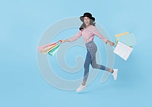 Jumping happy teen asian woman enjoying shopping, she is carrying shopping bags to get the latest offers at the shopping center