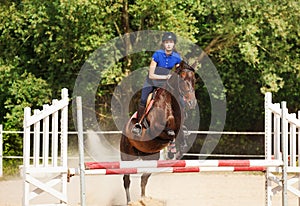 Jumping horse carrying horsewoman during training