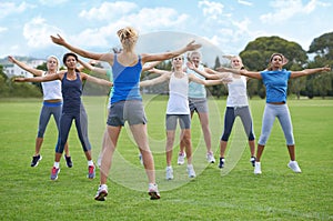 Jumping jacks, women and group outdoor for exercise on sports field and energy for cardio in fitness class. Health