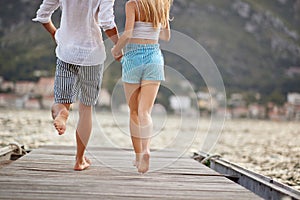 jumping with joy. Couple holding hands and run to jump in the water
