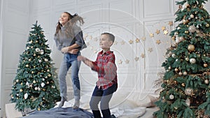 Jumping kids falling down on double bed in rest room.