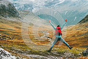 Jumping Man with backpack hands raised mountains landscape