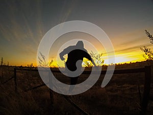 Jumping over the fence during sunrise in outback of Australia