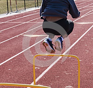 Jumping over two feet high yellow hurdles