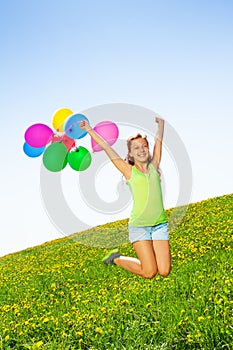 Jumping positive girl with balloons in summer